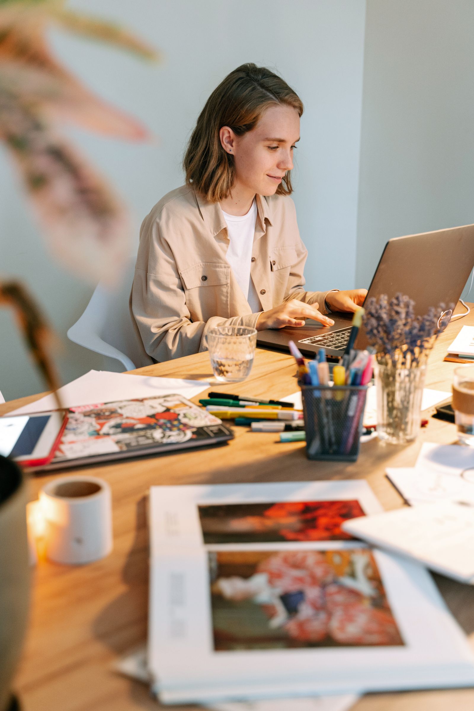 Designer working on a laptop in a creative studio with sketches and art materials