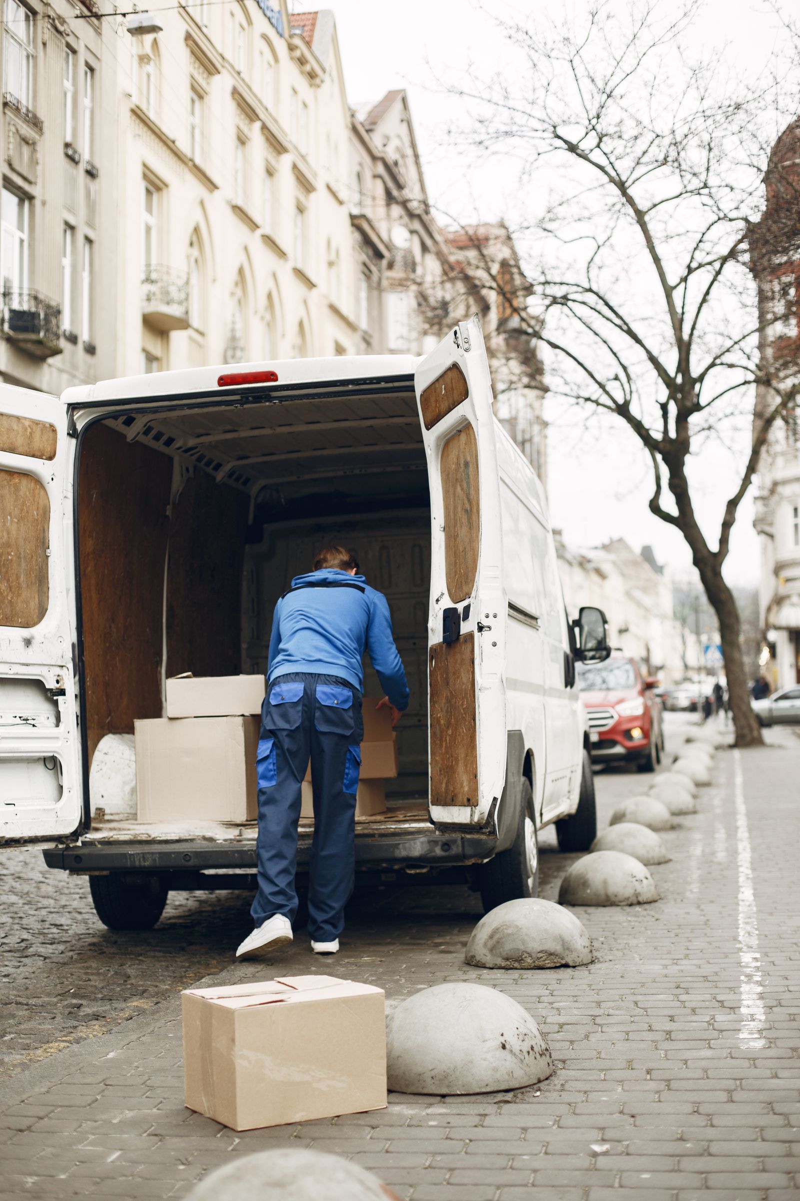 Moving and logistics worker loading packed boxes into a delivery van