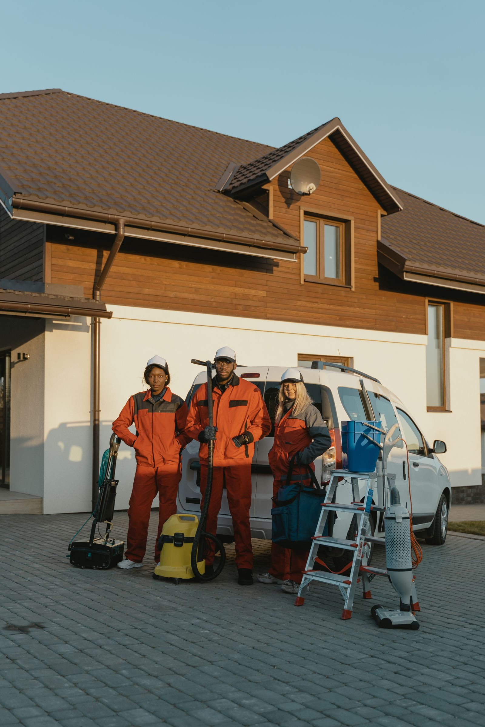Professional cleaning crew standing with equipment outside a modern home
